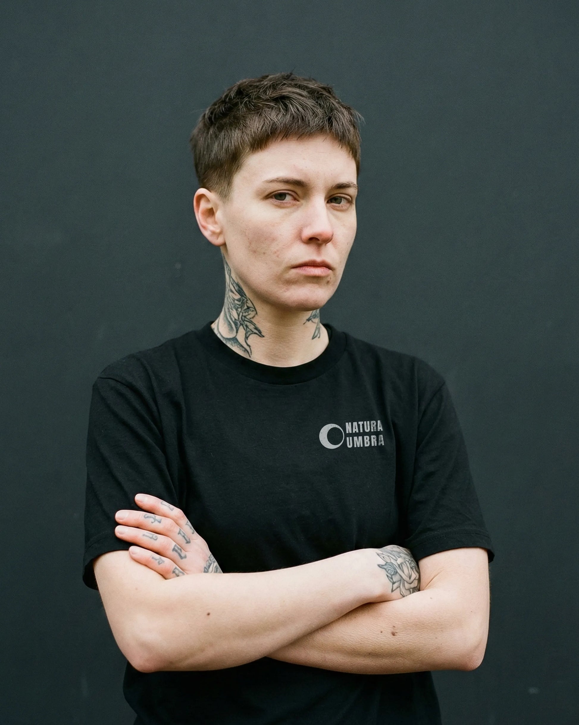 Androgynes Model trägt Stanley/Stella Creator 2.0 Bio Unisex T-Shirt in Schwarz mit "Natura Umbra" Frontprint – vegane Streetwear.