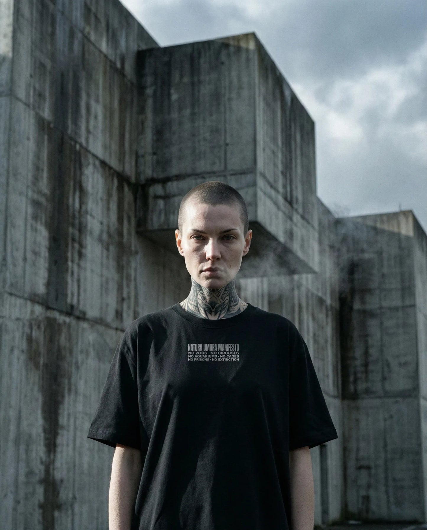 Model mit Stanley/Stella Freestyler T-Shirt in Schwarz – Frontprint "Manifesto" – Oversized Unisex Shirt aus Bio-Baumwolle.